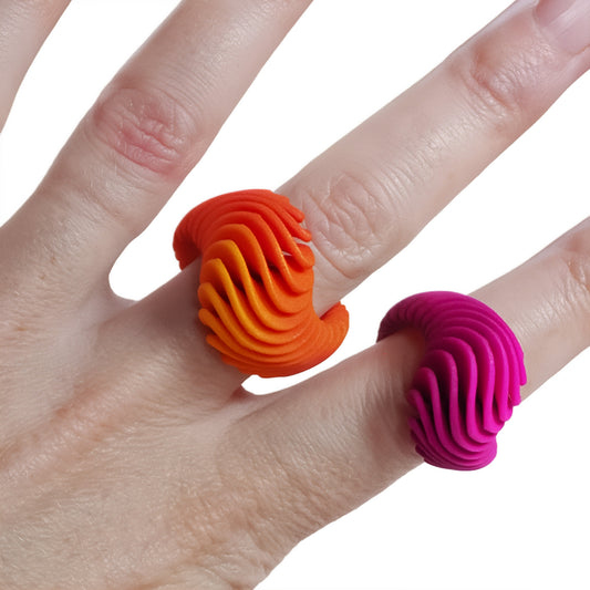 Two colourful Phase Jewellery 3D-printed rings on a person's fingers against a white background