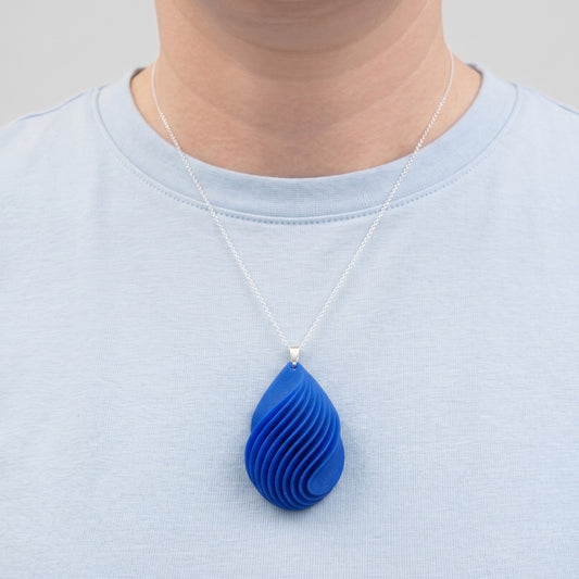 Blue teardrop pendant necklace on a person wearing a light blue shirt.
