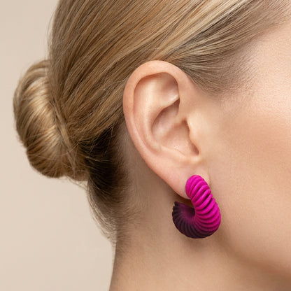 A pink Gradient 3d printed twisted hoop earrings on  an woman's ear by Phase Jewellery